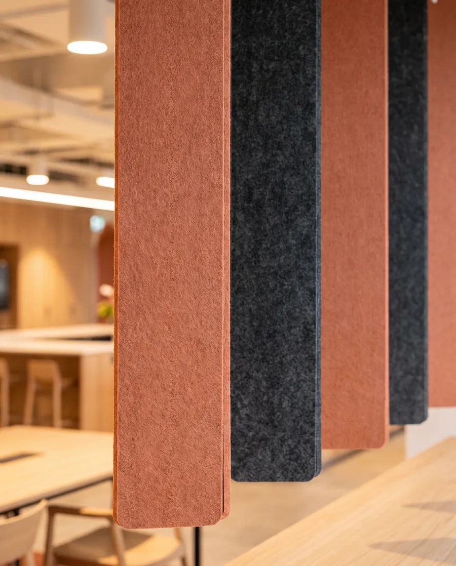 Gros plan de panneaux acoustiques hexagonaux en feutre PET, tons charbon et terracotta